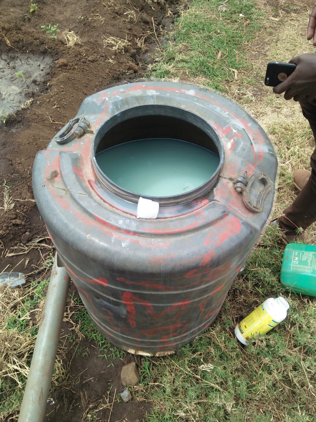 A water storage tank and irrigation supplies placed near the field.